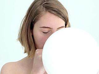 A young woman enjoys blowing up and popping her first sex toy that resembles an balloon.